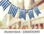 A garland of Greece national flags on an abstract blurred background.