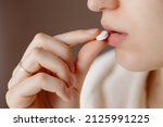 Small photo of Beautiful young woman taking pills, closeup. Sick ill woman holding antidepressant painkiller antibiotic pill glass of water take medicine, female handing tablet meds to mouth to relieve pain, health