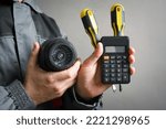 Calculation of the cost of installation of a video surveillance system concept. Video surveillance service worker holds a cctv security camera and calculator close up.