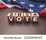 United States presidential election in 2024. Wooden cubes with text VOTE and 2024 over the American flag background. Politics and voting conceptual