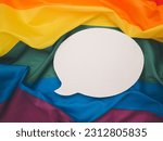 Top view of rainbow flag or LGBT flag with a blank white speech bubble. Close-up photo. Space for text. Gender diversity concept
