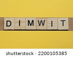 Small photo of the gray word dimwit of gray small wooden letters lies on a yellow table