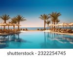 Luxurious beach resort with swimming pool and loungers umbrellas with palm trees