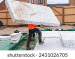 Small photo of Builder placing polystyrene insulation boards on waterproofing membrane during floor construction. Energy saving concept