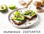 Healthy avocado toasts with rye bread, sliced avocado, cheese, pumpkin, nut and sesame for breakfast or lunch. Vegetarian food. Vegan menu. Food recipe background. Close up.