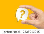 Small photo of Question mark design. Hand holding speech bubble with question mark on yellow background