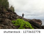 Small photo of Maui, Hawaii / USA - November 10, 2018: A young Asian woman looks out at the Pacific Ocean from a cliffside along the Ohai Trail Look in West Maui, north of the Nakalele Blowhole and Lahaina.