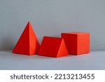 Small photo of Red abstract geometrical figures on gray background. bright three-dimensional pyramid rectangular cube objects. Platonic solids figures, simplicity concept photography