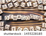 Small photo of demagogue wooden cubes with letters, populist exciting the emotions concept, around the cubes random letters, top view on wooden background