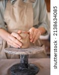 Small photo of Creative handicraft process woman artist uses tool for shaping and hand sculpting pottery. A working table in a workshop where a potter works with raw materials to create handicraft pottery