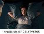 Small photo of Annoyed woman suffering neighbour noise in the bedroom at night at home. She can't sleep at night. Noise and insomnia concept. Copy space