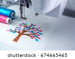 Close up picture workspace of  embroidery machine 
show embroider tree design theme. And two thread s cyan and pink color.