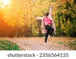 Woman ballerina in pointe shoes in golden autumn park, standing in beautiful pose on yellow leaves
