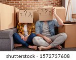 Small photo of Confused couple of having to move and arrange all the packages. Concept of success, delusion, change , future, confusion, question.