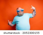Small photo of Fat delusion man with beard, tattoos and sunglasses is uncertain for something