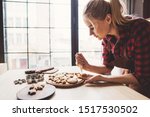 Christmas bakery. Woman decorating Christmas gingerbread cookies with sugar icing. Festive food, cooking process, family culinary, Christmas and New Year traditions concept