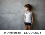 Profile portrait of a handsome little boy in underwear posing on concrete wall, looking a one side, copy space.