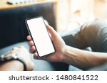 Mockup image blank screen cell phone.men hand holding texting using mobile on sofa at home office.white empty space for advertise text. contact business,people communication,technology device concept