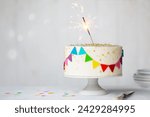 Celebration birthday cake with colorful rainbow bunting and a celebration sparkler