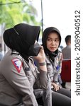 Small photo of Makassar, Indonesia - December 8 2021: Two Indonesian policewomen are sitting talking while holding the phone