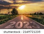 Empty asphalt road and New year 2023 concept. Driving on an empty road to Goals 2023 with sunset.
