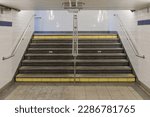 Subway stairs with hand rails, low ceilings and tiled walls in downtown Manhattan