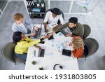 Small photo of Competent IT specialists in stylish outfit working on modern gadgets while sitting together at bright office. Young multiracial people shaking hands, talking and smiling during cooperation.