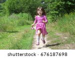 Adorable little girl in pink dress runs in the fores. Sunny summer day