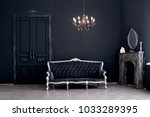 Black room in the castle with a vintage door, a chandelier, a sofa  and amirror and fireplace. Space where you can mount a person.