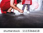 Small photo of "Tie Shoes" with Mother & Baby (People) and Recreation Outdoor Concept. Selective focus Asian mom helping infix a rope of her Daughter sneaker-shoes on concrete floor, They be wearing a red clothes.