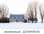 Pretty traditional French style stone house with metal sheet roof and smaller wooden shed seen at in the early morning, Beaumont, Quebec, Canada
