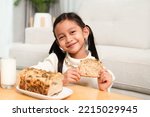 Small photo of Asian little girl is eating multigrain whole whet homemade bread and drink milk with happy moment. Concept of healthy food and lifestyle, nutrition, natural food for children in family life.