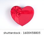 Red gift box heart shape with red ribbon on white background, gift concept Valentine day, top wiev, copy space
