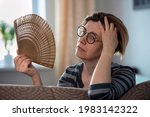 Small photo of Exhausted middle aged woman waving her fan, suffering from menopausal symptoms, experiencing hot flush.