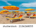 Bright orange parasols and deck chairs on the beach in Rimini, Italy. 