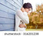 Beautiful natural young brunette woman wearing knitted sweater by the house. Fall and winter fashion concept.