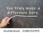 Small photo of Male hand writes in white chalk pencil the word you truly make a difference here a chalkboard background. Encouragement words.