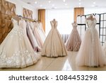 Beautiful wedding dresses, bridal dress hanging on hangers and mannequin in studio. Fashion look. Interior of bridal salon.