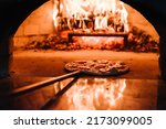Small photo of The chef puts the Margherita, four cheese or meat pizza on a shovel in the oven. A firewood oven for cooking and baking pizza. Italian traditional pizza is cooked in a stone wood-fired oven.