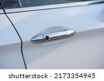 Car door handle with keyless go sensor. Automatic opening of a car door without a key. Exterior design of a new white luxury car. Closeup.