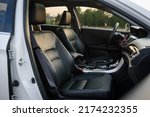 Modern luxury car standing at parking. Interior of prestige new car. Comfortable perforated leather seats. Car detailing series. Side view of the open passenger door, dashboard of car.