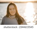 Female walk on sand near lake in park with sunlight. Portrait woman or mom on beach of nature. Family spending time at sunset on vacation. Concept of autumn holiday. Spring mood photo. Autumn girl