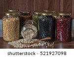 Shiift white bean on wooden spoon and Various dried legumes on a glass jar