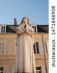 Small photo of total statue of Bernadette Soubiroux, Nevers, France. With the monastery in the back and a blue sky