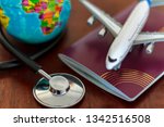 Global Healthcare and travel insurance concept. Passport Stethoscope, airplane and globe on wooden table