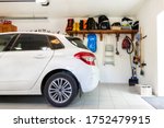 Home suburban car garage interior with wooden shelf , tools and equipment stuff storage warehouse on white wall indoors. Vehicle parked at house parking background