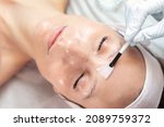 Close-up beautician doctor hand making anti-age procedure apply peeling acid young attractive female client at beauty clinic. Cosmetologist specialist doing skincare treatment. Health care therapy