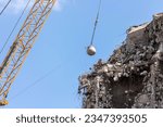 Heavy wrecking ball crane demolishing old building against blue sky in Magdeburg Germany. Building dismantling and construction waste disposal recycling service