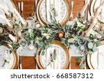 Aerial view of winter green garland on a wedding receptions head table with gold place setting and candelabra