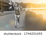 Small photo of Athletic, middle age female during her running cession along the river